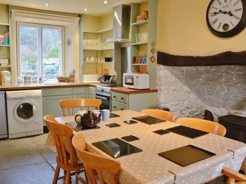 a kitchen with a table with chairs and a clock on the wall at 1 Tan-y-castell in Dolwyddelan