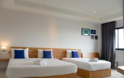 two beds in a hotel room with blue pillows at B Boutique Residence in Suratthani