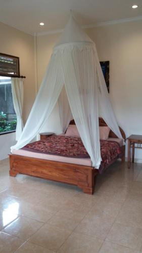 a bed with a canopy in a room at Arjana Bungalows Rice Field in Ubud
