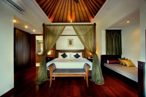 a bedroom with a bed and a canopy bed with a bench at The Khayangan Dreams Villa, Seminyak in Seminyak