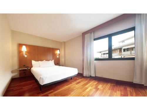 a bedroom with a bed and a large window at Hotel Ciutat Martorell in Martorell