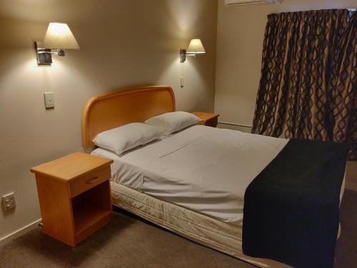 1 dormitorio con 1 cama con mesita de noche y ventana en Rayland Epsom Motel, en Auckland