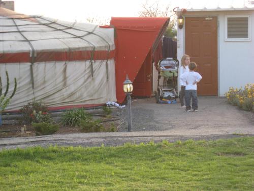 two children standing outside of a house with a tent at Sea of Galilee - Genghis Khan in The Golan in Giv'at Yo'av