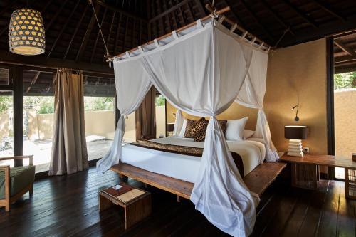 um quarto com uma cama e uma rede mosquiteira em NusaBay Menjangan em Banyuwedang