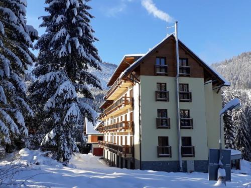 a building in the snow next to a tree at Apartment No.7 Lúčky - Jasná in Belá