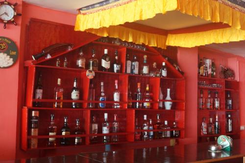 a bar with a red shelf filled with lots of bottles at Royal Wood Beach Resort in Palolem