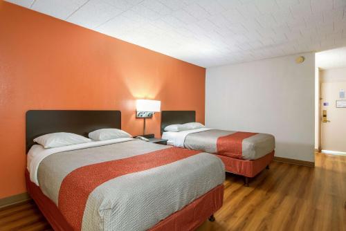 two beds in a room with orange walls at Motel 6-New Stanton, PA in New Stanton