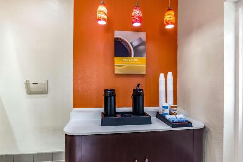a bathroom with an orange wall with a coffee maker on a counter at Motel 6-Raleigh, NC - Cary in Cary
