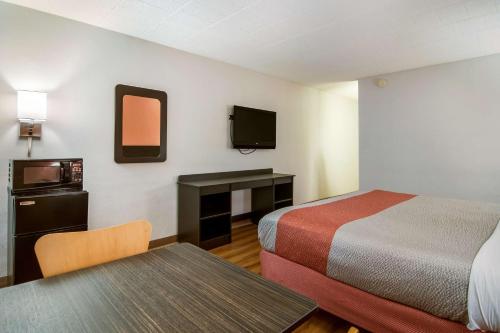 Motel 6-New Stanton, PA في نيو ستانتون: غرفة فندقية بسريرين وطاولة وتلفزيون