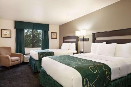 a hotel room with two beds and a chair at Baymont by Wyndham Hearne in Hearne