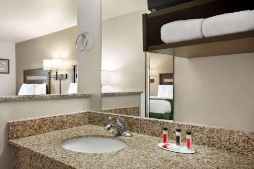 a bathroom with a sink and a large mirror at Baymont by Wyndham Hearne in Hearne