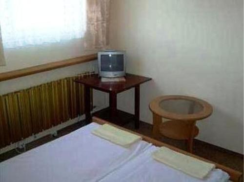 Cette chambre comprend un lit et une table avec une télévision. dans l'établissement U Joanny, à Piaseczno