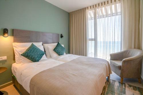 a bedroom with a large bed with a chair and a window at Roxon Sea Sand Bat Yam in Bat Yam