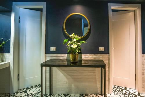a table with a mirror and a vase with flowers on it at Roxon Sea Sand Bat Yam in Bat Yam