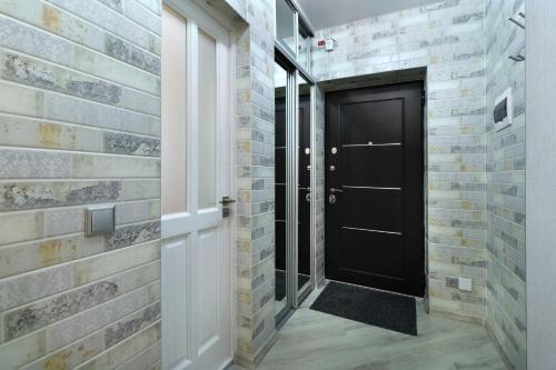 a hallway with a black door and a brick wall at PaulMarie Apartments on Yakubovskogo in Mogilev