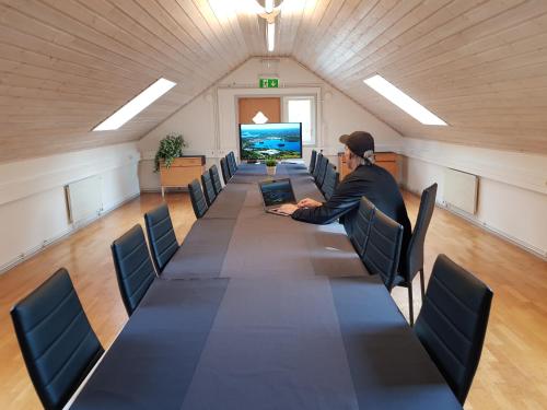 a man sitting at a long table in a room with a laptop at Brukshotellet Skinnsberg in Skinnskatteberg