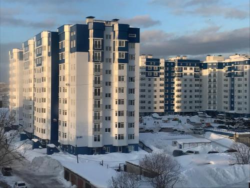 um grande edifício de apartamentos com neve no chão em Hostel Ovsyanka em Yuzhno-Sakhalinsk