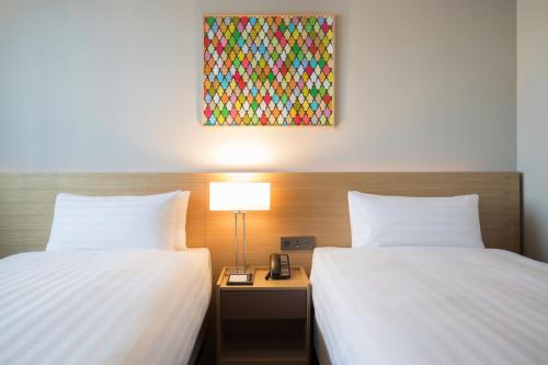 two beds in a hotel room with a lamp between them at Orakai Cheonggyesan Hotel, BW Premier Collection in Seoul