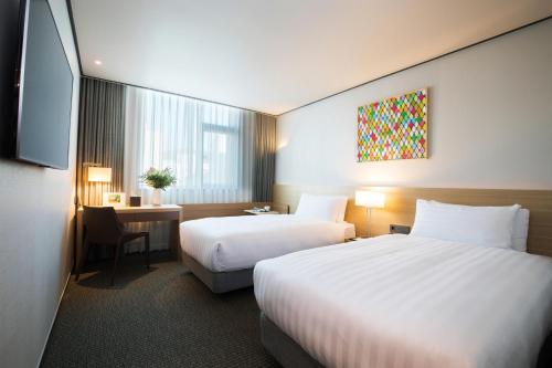 a hotel room with two beds and a tv at Orakai Cheonggyesan Hotel, BW Premier Collection in Seoul