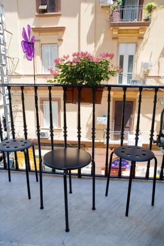 a balcony with three chairs and a flower planter at Hotel Cineholiday in Naples