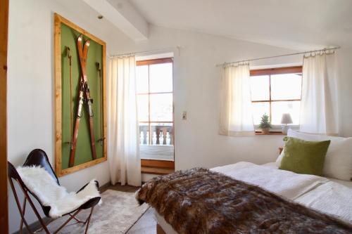 a bedroom with a bed and a chair and windows at BELLE KITZ im Zentrum by Belle Stay in Kitzbühel