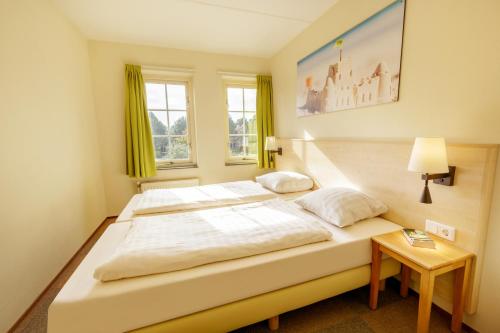 a large white bed in a room with a table at Center Parcs Port Zélande beach in Ouddorp