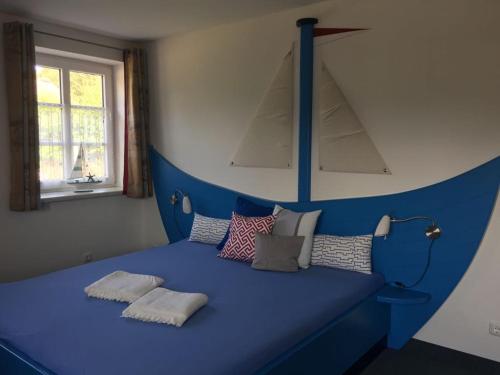 una cama azul con almohadas en una habitación en Hotel Garni Sössaarep's Hüs, en Nebel
