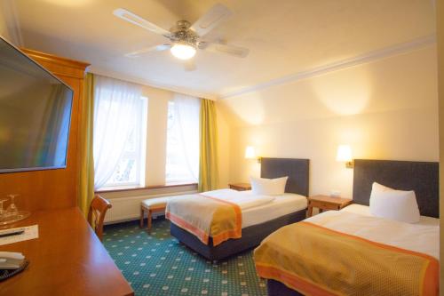 a hotel room with two beds and a flat screen tv at Stadthotel Herzog Ludwig in Landshut
