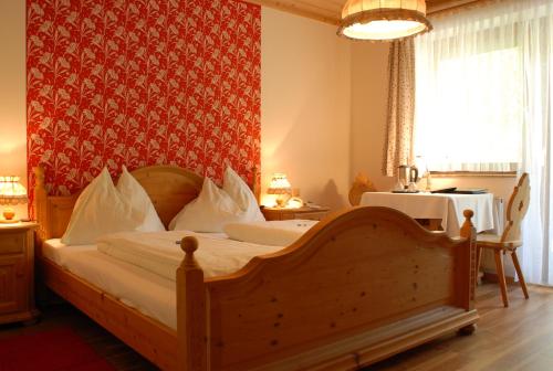 um quarto com uma cama de madeira e uma parede vermelha em Bärnthaler Gasthof Restaurant em Bad Sankt Leonhard im Lavanttal