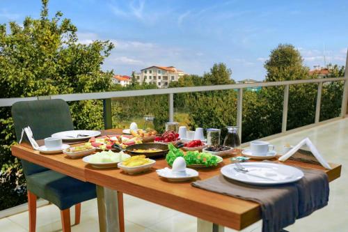 einen Holztisch mit Essen auf dem Balkon in der Unterkunft Helenapolis Otel in Altınova