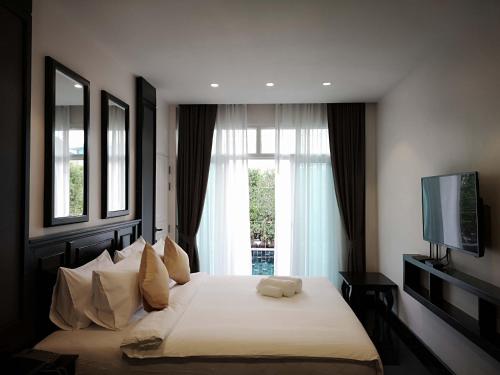 a bedroom with a bed with a television and a window at T Villas Hua Hin in Khao Tao