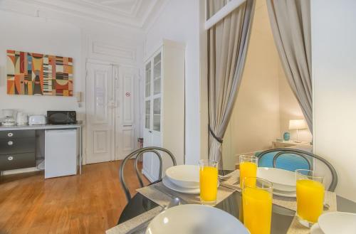 ein Esszimmer mit einem Tisch, Stühlen und Orangensaft in der Unterkunft Chiado Balcony Apartment in Lissabon