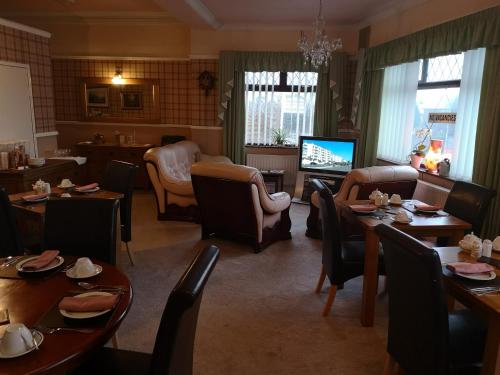 a dining room with tables and chairs and a television at East Mount House in Barrow in Furness