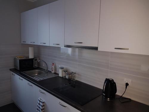 a kitchen counter with a sink and white cabinets at Arkadia Hostel in Mława