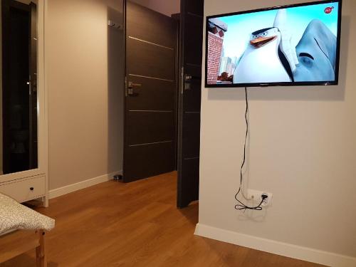 una TV a schermo piatto appesa a un muro in una camera di Arkadia Hostel a Mława