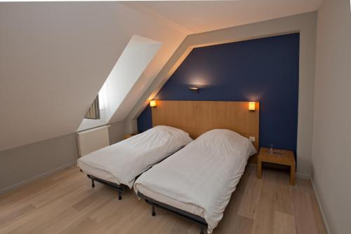 a bedroom with a bed and a blue wall at Hotel De Zalm in Herentals