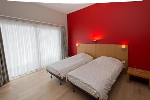 a bedroom with a red wall and two beds at Hotel De Zalm in Herentals