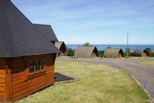 een groep houten gebouwen met de oceaan op de achtergrond bij Pot a Doodle Do in Berwick-Upon-Tweed