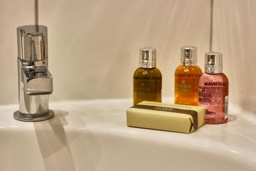 three bottles of essential oils and a book on a sink at Portfolio Apartments - St Albans City Centre in St. Albans