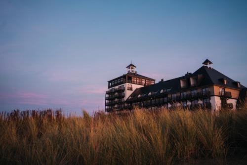 a building sitting on top of a field of tall grass at Strandhotel in Cadzand-Bad