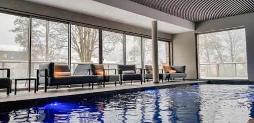 - une piscine avec des canapés et des chaises dans un bâtiment dans l'établissement Hôtel Interlaken Lounge Bar & Spa, à Xonrupt-Longemer