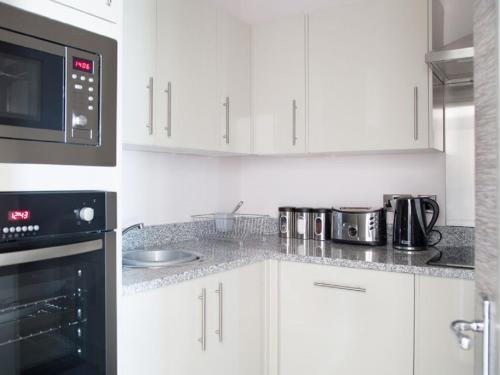 a kitchen with white cabinets and a black microwave at Harrogate Lifestyle Luxury Serviced ApartHotel in Harrogate