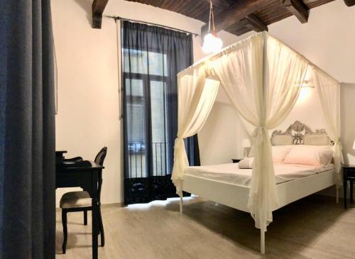 een slaapkamer met een hemelbed en een bureau bij Teatro Nuovo Apartment in Napels