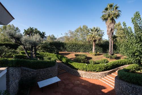 a garden with a bench and palm trees and bushes at Il Giardino di Venere in Mondello