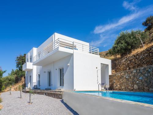 une maison blanche avec une piscine à côté d'un mur en pierre dans l'établissement Villa Mariou, à Plakias