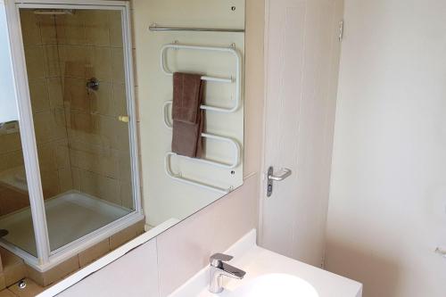 uma casa de banho com um lavatório, um chuveiro e um espelho. em On the Beach 2 em Langebaan