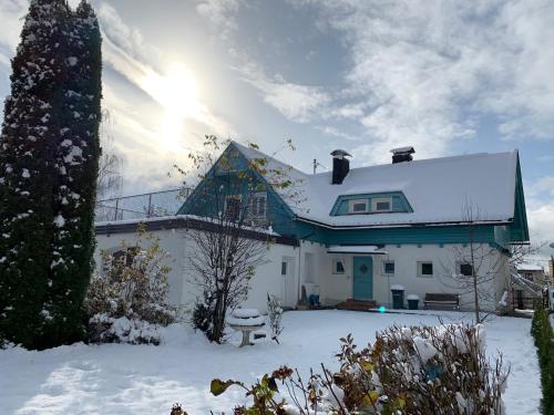 a house covered in snow with the sun behind it at Blaues Haus Ferienwohnung Bodensdorf Ossiacher See Gerlitzen Alpe in Bodensdorf