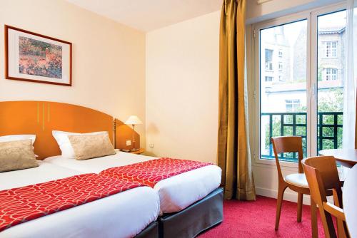 a hotel room with a bed and a table and a window at Hotel Vacances Bleues Villa Modigliani in Paris