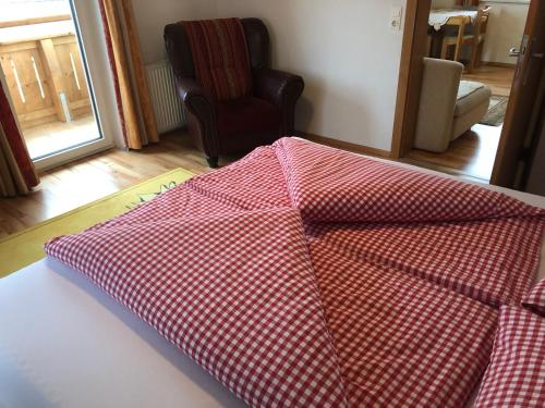 a red and white checkered blanket sitting on a bed at Pension Waldegg in Hippach
