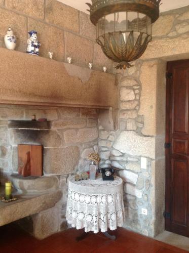 a stone room with a table in front of a fireplace at Casa Boavista in Paredes de Coura